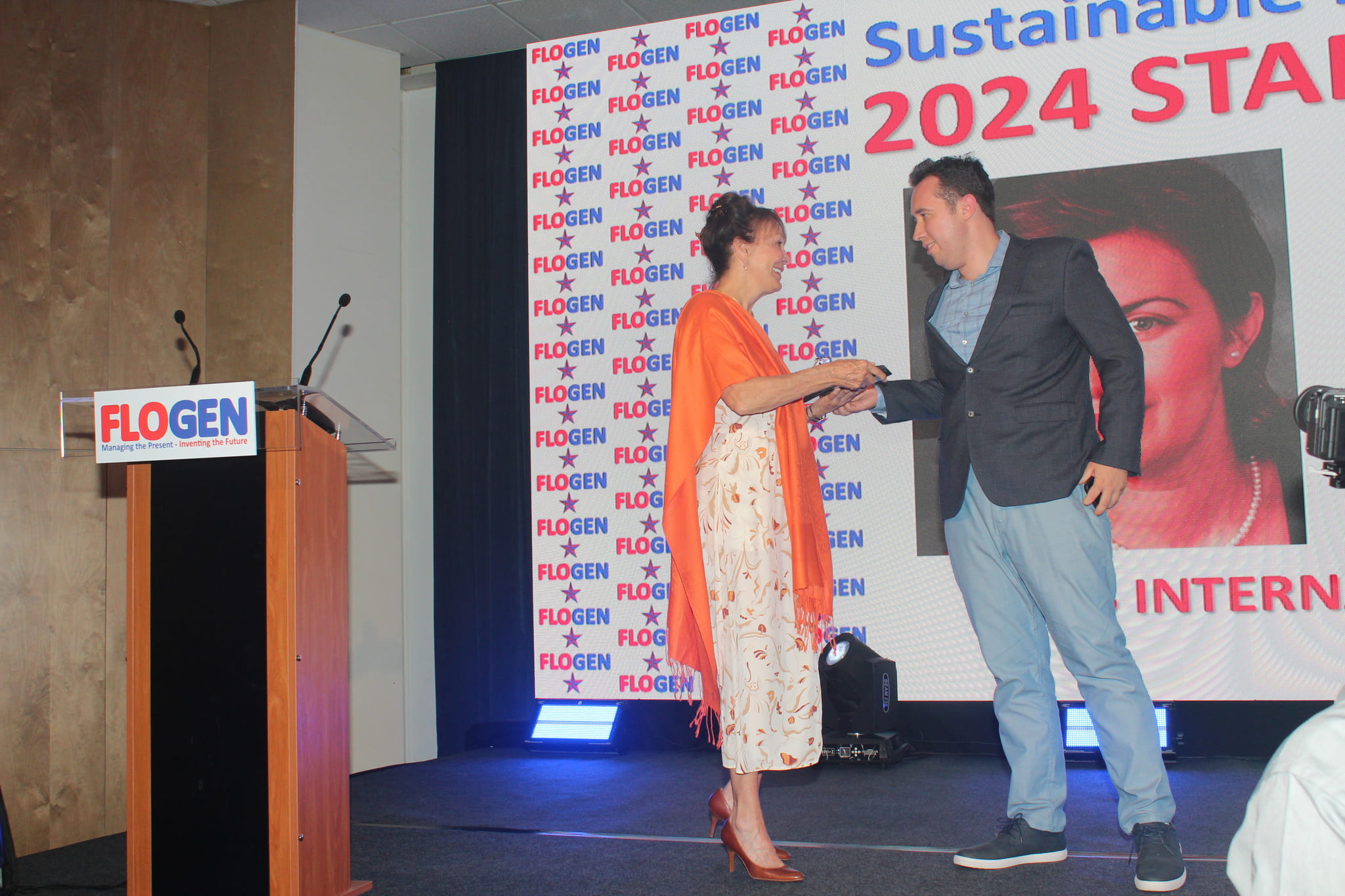 Honorable Louise Otis congratulating Davis Joseph on behalf of Me. Migen Dibra during the FLOGEN SIPS 2024 award ceremony