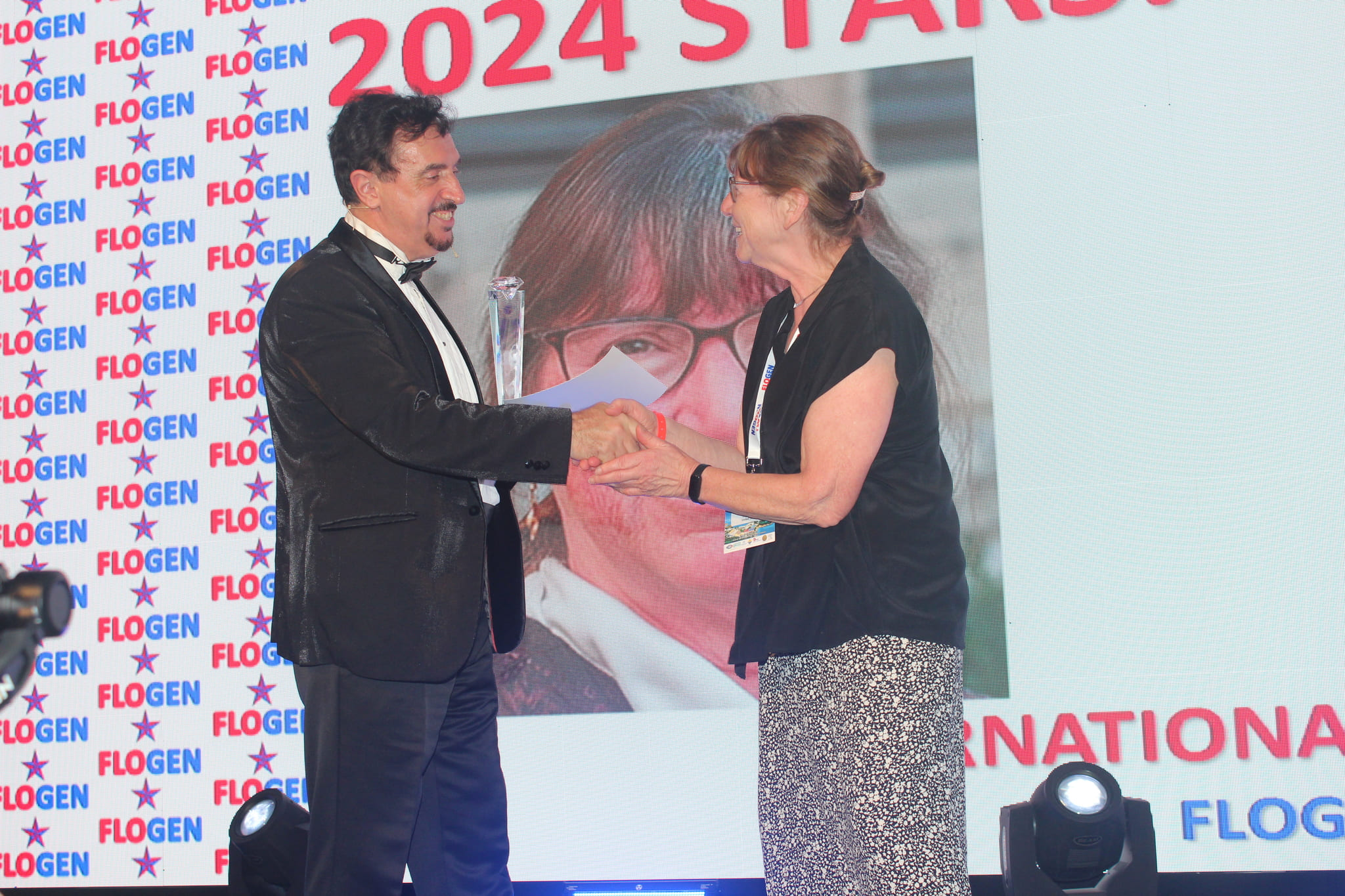 Dr. Florian Kongoli congratulating Dr. Nancy Ross during the FLOGEN SIPS 2024 award ceremony