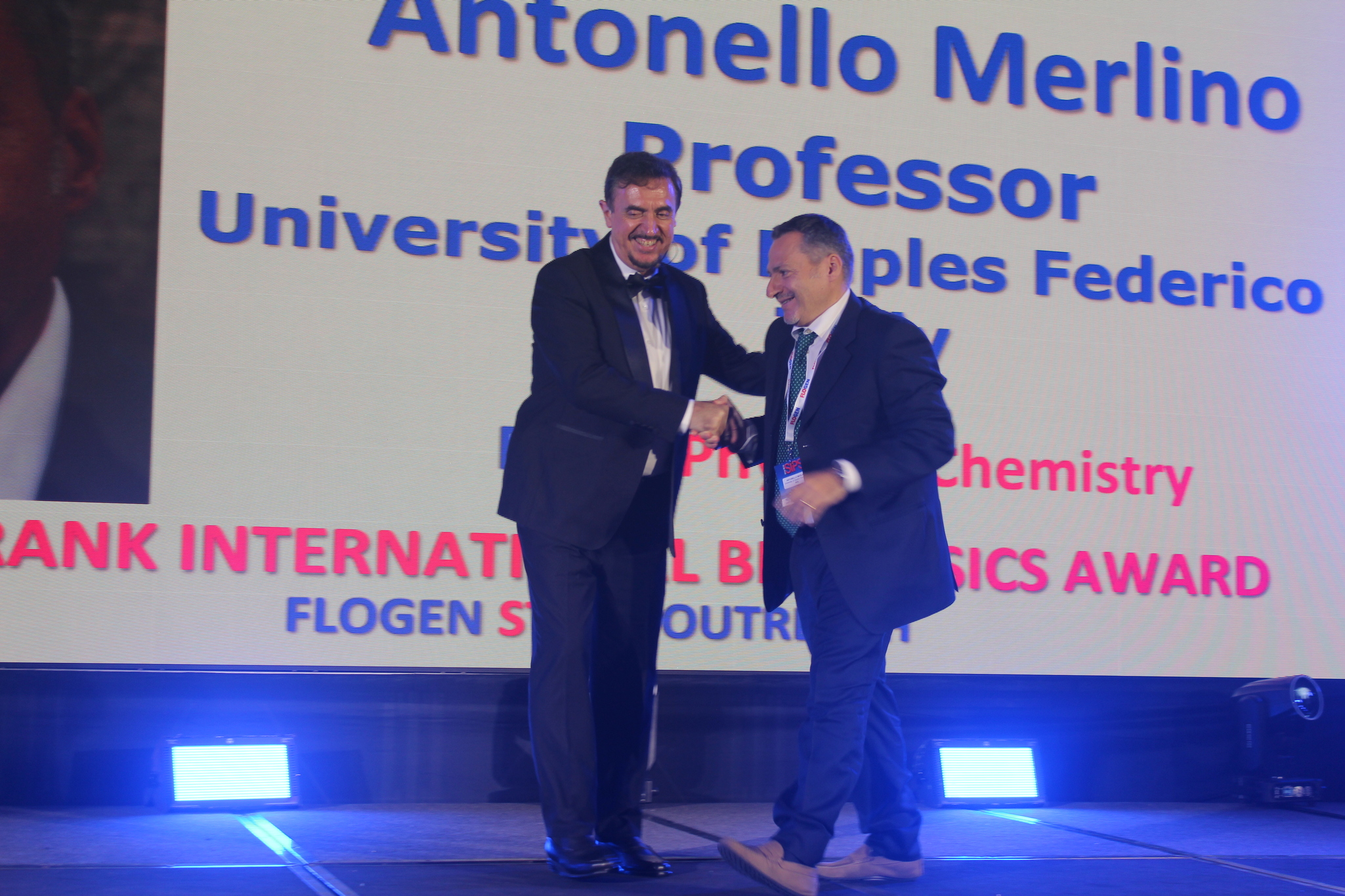 Dr. Florian Kongoli congratulating Dr. Antonello Merlino during the FLOGEN SIPS 2025 award ceremony